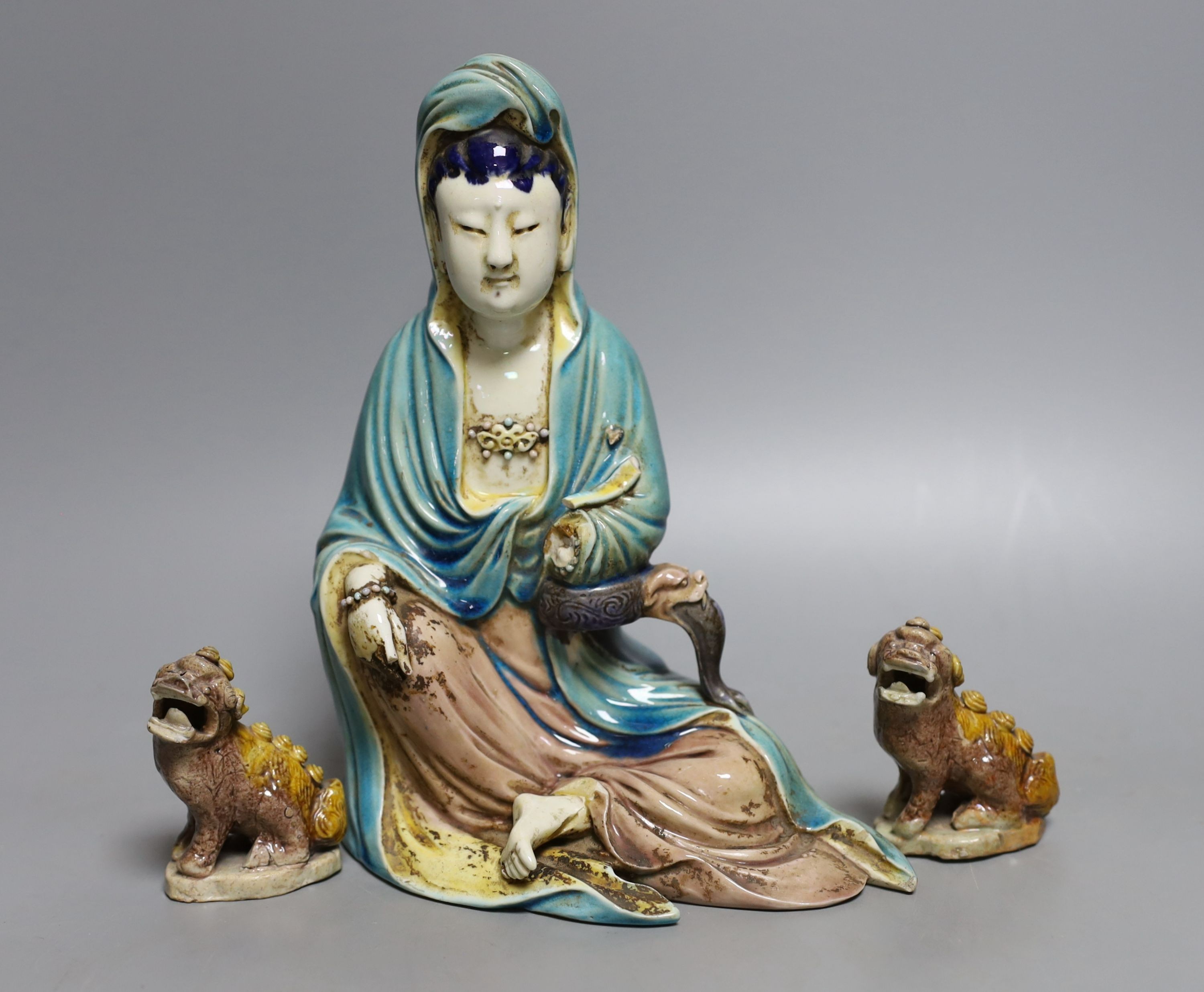 An early 20th century Chinese polychrome porcelain figure of Guanyin, 21cm tall, and two dogs